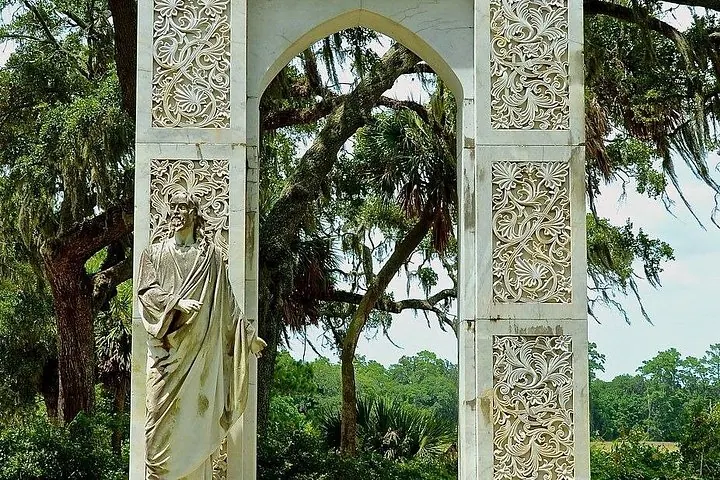 A statue of Jesus standing beneath an intricately carved stone archway.
